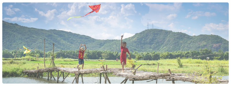 Kids fly a kite over a bridge